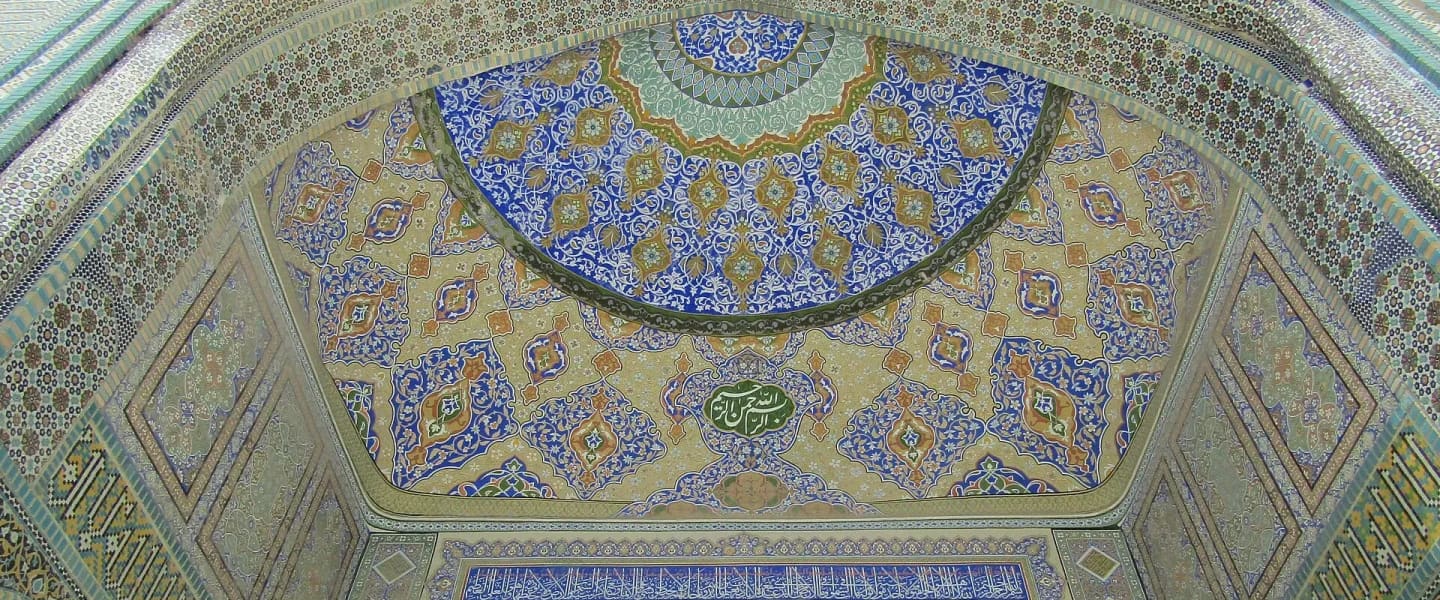 A tall arched entrance covered in blue, white and yellow tile mosaic.